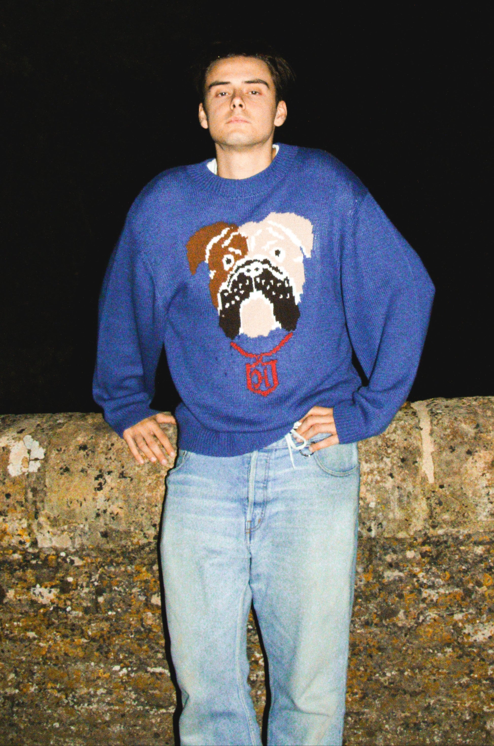 Person wearing a blue sweater with a bulldog design against a dark background